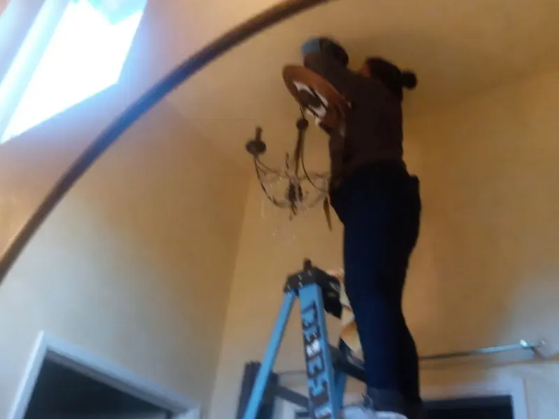 Electrician installing a chandelier in a Santee residence